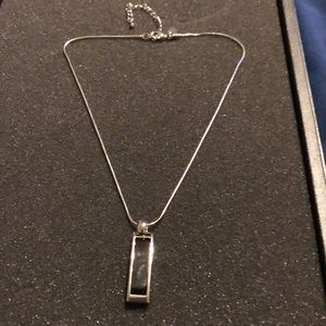 Silver necklace with black and white charm.